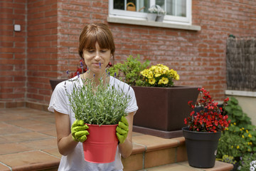 Mujer joven con plantas delante de su casa