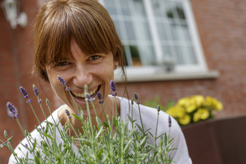 Mujer joven con plantas delante de su casa