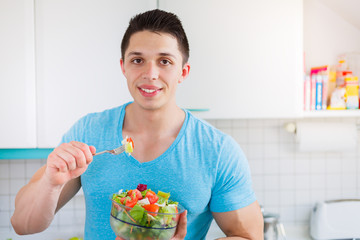 Salat essen junger Mann isst in der Küche gesunde Ernährung vegan Textfreiraum