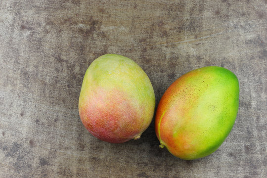 two fresh mango fruits on a grungy metal background