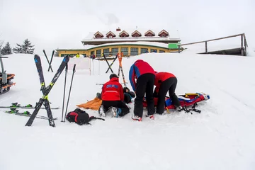 Fotobehang Kameraden der Bergwacht versorgen eine gestürzte und verletzte Skifahrerin © benjaminnolte