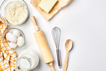Preparation of the dough. A measurement of the amount of ingredients in the recipe. Ingredients for the dough: flour, eggs, rolling pin, whisk, milk, butter, cream. Top view, space for text