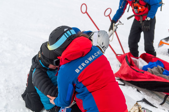 Kameraden der Bergwacht versorgen eine gest&uuml;rzte und verletzte Skifahrerin