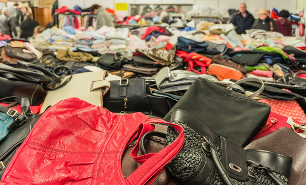 Verkauf Secondhand Grabbeltisch mit Handtaschen und K&auml;ufer im Hintergrund - Sale second-hand table with handbags and buyers in the background