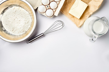 Preparation of the dough. A measurement of the amount of ingredients in the recipe. Ingredients for the dough: flour, eggs, rolling pin, whisk, milk, butter, cream. Top view, space for text