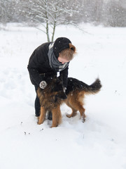 Woman playing with dog shepherd dog in the snow in winter