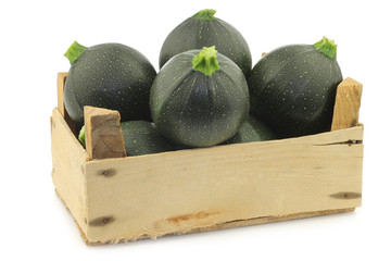 Green zucchini's (Cucurbita pepo) in a wooden crate on a white background