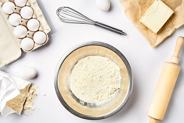 Preparation of the dough. A measurement of the amount of ingredients in the recipe. Ingredients for the dough: flour, eggs, rolling pin, whisk, butter. Top view, space for text