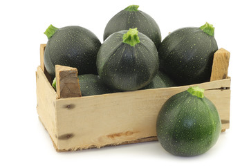 Green zucchini's (Cucurbita pepo) in a wooden crate on a white background