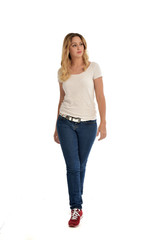 Fototapeta premium full length portrait of blonde girl wearing white shirt and jeans. standing pose, isolated on white studio background.