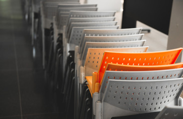 Orange chair among white chairs. Minimal style. plastic chairs. 
