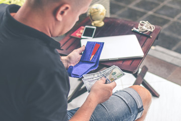 Man doing online shopping with credit card, laptop and luxury snakeskin python wallet. Man online...