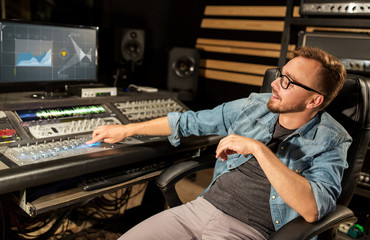 man at mixing console in music recording studio
