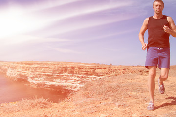 Running and a healthy lifestyle. A man runs along the beach. 