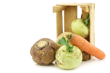 mixed cabbage and root vegetables in a wooden crate on a white background