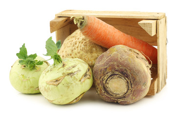 mixed cabbage and root vegetables in a wooden crate on a white background