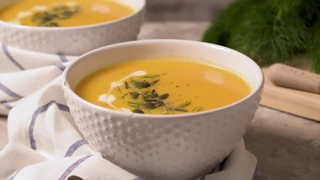 Delicious creamy homemade pumpkin soup with cream and pumpkin seed garnish.