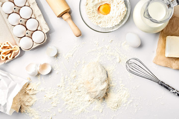 Raw dough ready for kneading on white table. Bakery ingredients, eggs, flour, butter. Shapes for making cookies.