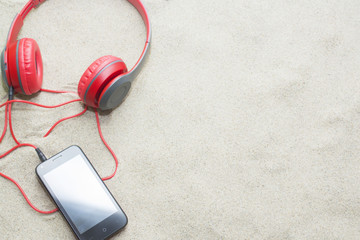 phone with headphones on sand in a summer beach.