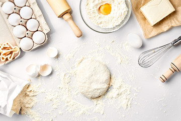 Raw dough ready for kneading on white table. Bakery ingredients, eggs, flour, butter. Shapes for...