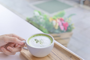 Hot Matcha green tea latte beverage in cup on wooden table.