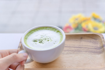 Hot Matcha green tea latte beverage in cup on wooden table.