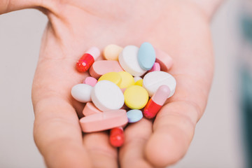 Closeup of a man holding colorful pills in his right hand