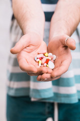 Closeup of a man holding colorful pills in his right hand