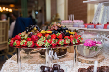 A lot of strawberry and grape on the tray. Wedding candy bar.