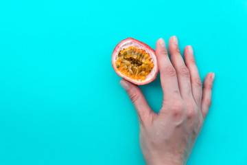 Female hand with Passion fruit on blue background
