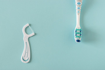 Toothbrush and dental floss on bright blue background.