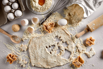 Baking concept: raw dough for biscuit, eggs, flour, cutters in the shape of star and butterfly on a white table. Top view.