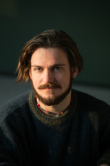 Obraz premium Portrait of hadsome young bearded stylish man sitting on the chair in studio