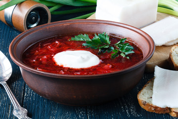 Borscht beetroot soup, on the table with slices of rye cereal bread and sour cream. Rustic style