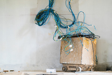 Old rusted inverter Welders with electric wires. with cement wall and iron tube on the ground.