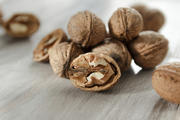 A handful of walnuts lie on a light wooden table
