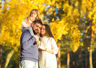 mom and dad with daughter at sunset in the woods play