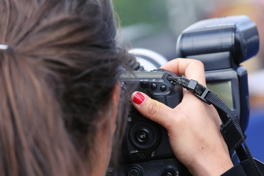 Close up of woman photographer taking a photograph with her professional digital photographic camera