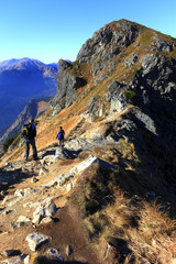 Fototapeta premium Zakopane, Tatra Mountains / Poland - 2010/07/04: Tourists on a trekking track heading to Goryczkowa Czuba peaks, Tomanowa Liptowska Valley and Czerwone Wierchy peaks with Western Tatra in background