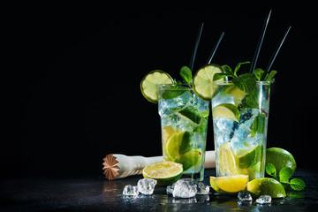 Two glasses of mojito cocktail with fresh lime and mint - obrazy, fototapety, plakaty