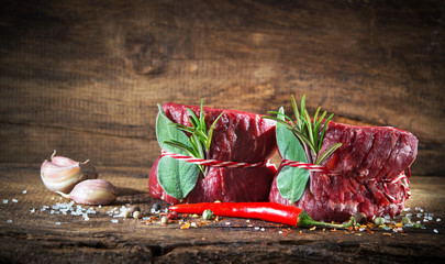 Raw beef fillet steaks mignon on wooden background