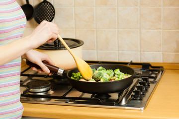 Woman cooking stir fry frozen vegetable on pan