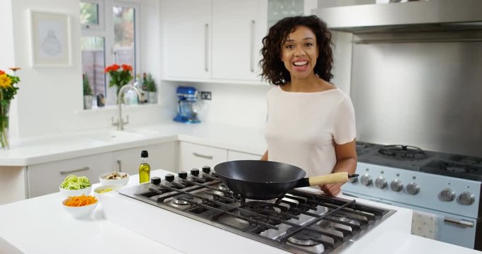 4K Smiling woman in modern kitchen preparing a healthy meal & talking to camera for TV show or internet vlog