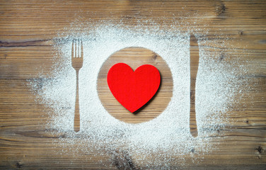 Fork, knife and plate with red heart, flour sprinkled around the cutting board