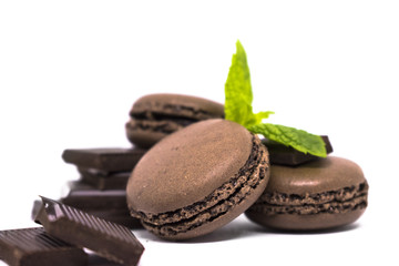 chocolate or coffee taste french macaroons decorated mint leafs, isolated on white background, selective focus