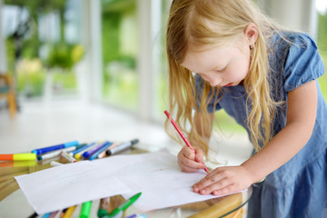 Cute little girl drawing with colorful pencils at a daycare. Creative kid painting at school