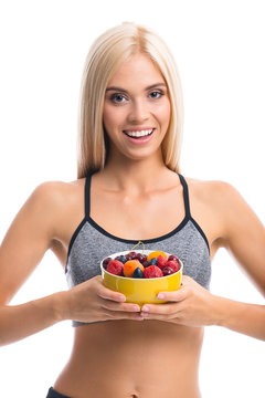 Woman in sportswear with plate of fruits, isolated