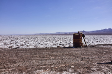 Fototapeta na wymiar Rusty Metal Barrel and Wooden Sing in the Atacama Desert