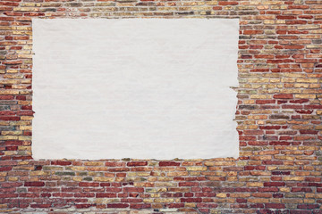 blank advertising poster glued to the brick wall