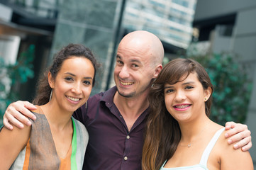 Obraz premium A handsome guy hugs joyful girls and smile